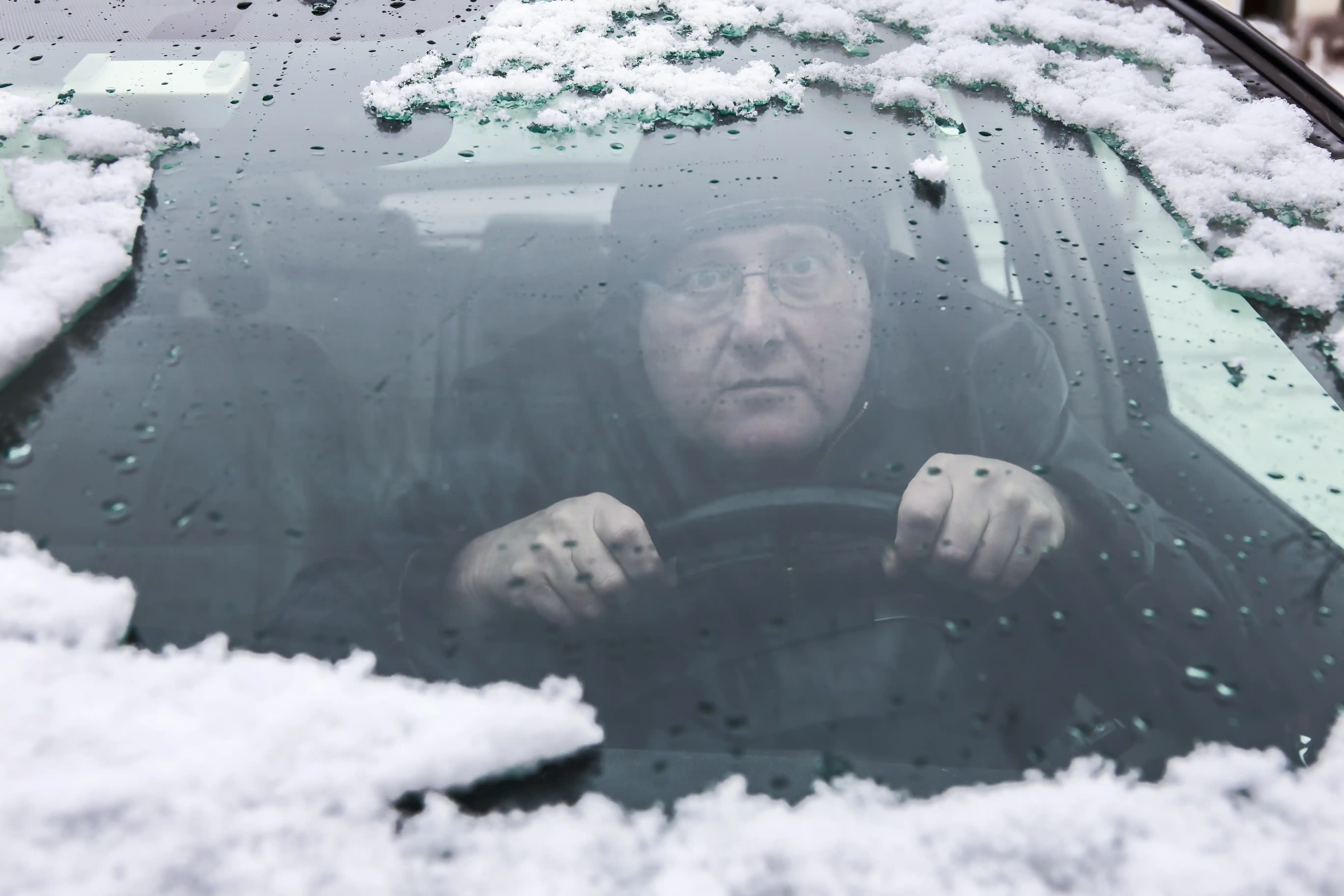 Driver behind a fogged and snowy windshield showing the difficulty of managing without clear data